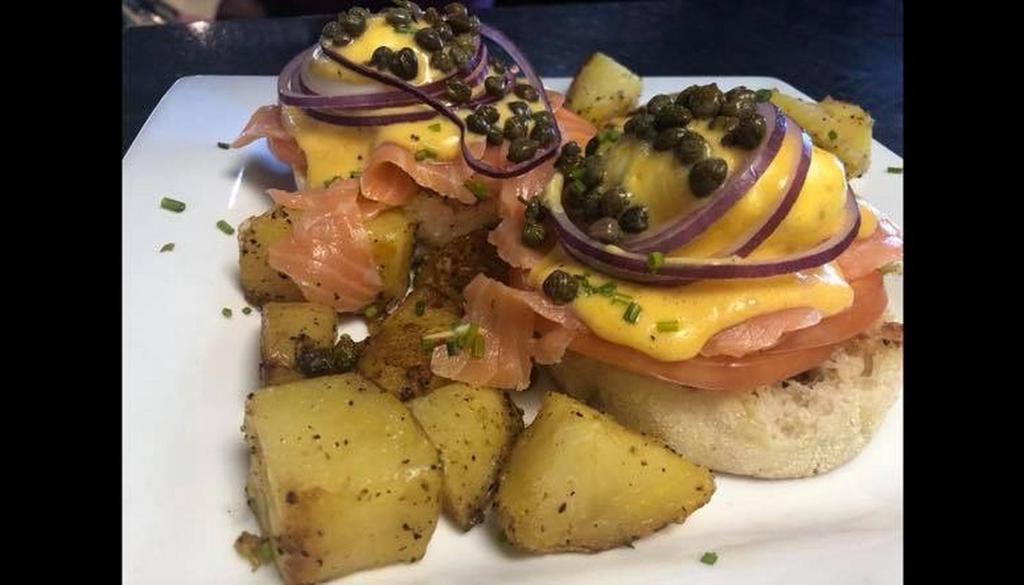 Lox Bennie · Toasted English muffin, poached eggs, smoked salmon, sliced tomato, red onion, capers, and chives topped with home-made hollandaise sauce. Served with potatoes.