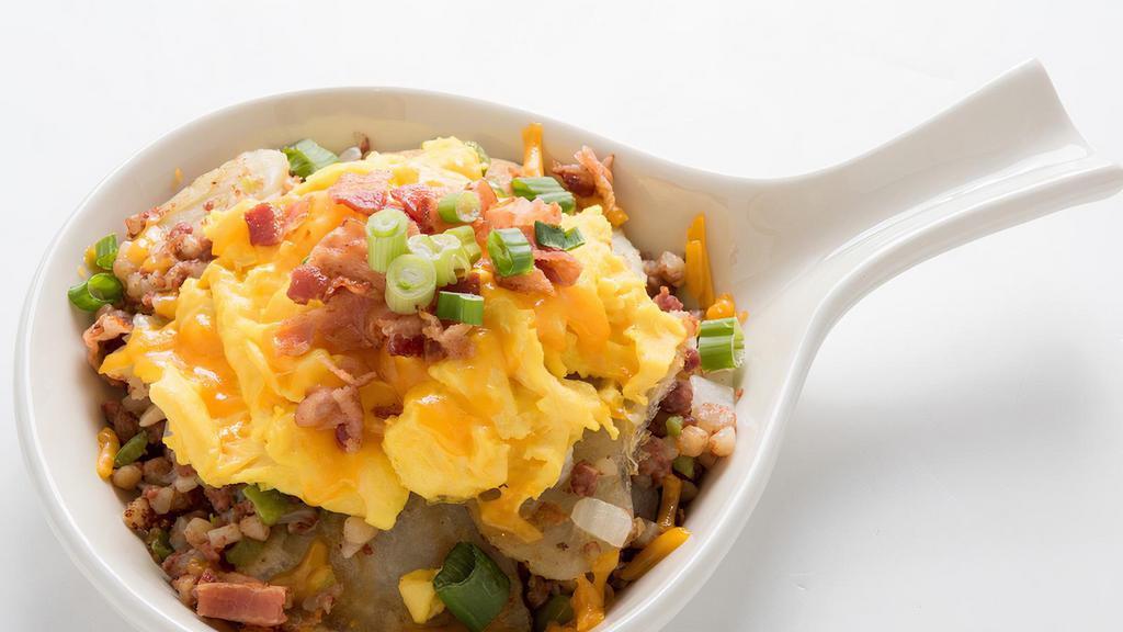 Hash Skillet · Home fried potatoes sautéed with corned beef hash, onions, and bell peppers. Topped with scrambled eggs, cheddar cheese, chopped bacon, and green onion