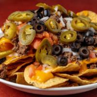 Grande Nachos · Fresh tortilla chips covered in nacho cheese sauce, choice of taco meat or chicken, and jala...