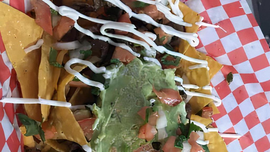 Nachos · Tortilla chips topped with nacho cheese, choice of meat, pico, guac and sour cream
