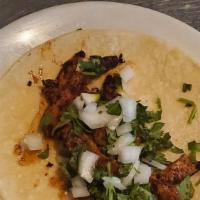 Marinated Pork Taco · Made with a soft corn tortilla filled with cilantro and onion.