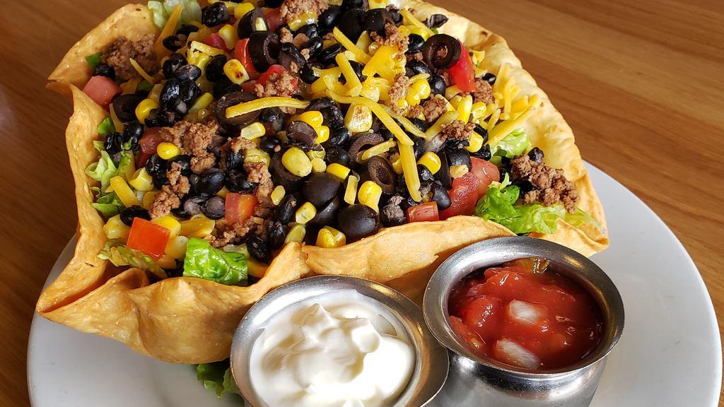 Taco Salad · CRISP GREENS, SEASONED GROUND BEEF, TILLAMOOK CHEDDAR CHEESE, TOMATOES, AND OLIVES, NESTLED IN A CRISP FLOUR TORTILLA, TOPPED WITH SOUR CREAM AND FRESH SALSA.