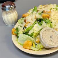 Caesar Salad · Crisp romaine tossed with croutons, Caesar dressing on the side, and grated cheese.