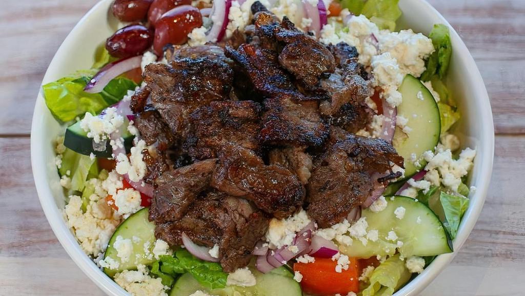 Beef Shawerma Salad · Served with lettuce, tomatoes, onions, cucumbers, feta cheese, olives, tzatziki or tahini sauce, and two pieces of pita. Topped with beef shawarma slices.