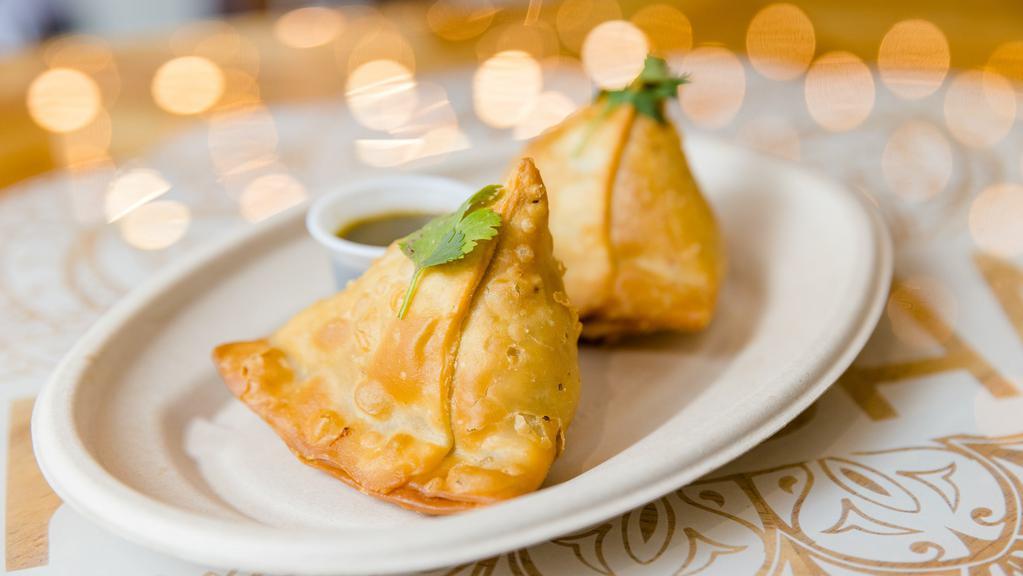 Samosa (2 Ct.) · Two crispy pastries stuffed with potatoes, peas, and secret spices.  
Served with a tamarind + chutney.