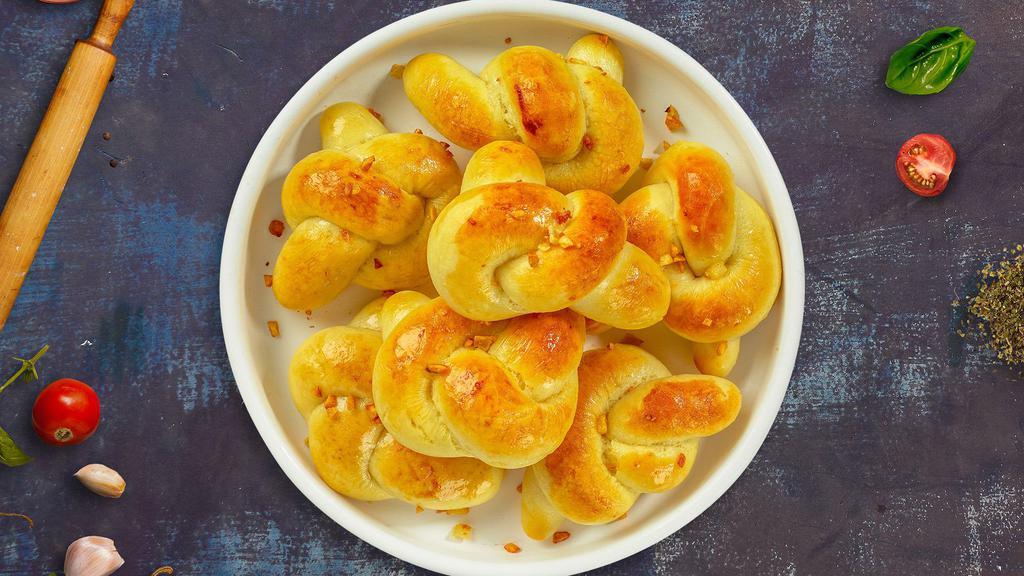 Tie The Garlic Knots · Our house made pizza dough, knotted up, baked, then smothered in real garlic butter and parmesan cheese.