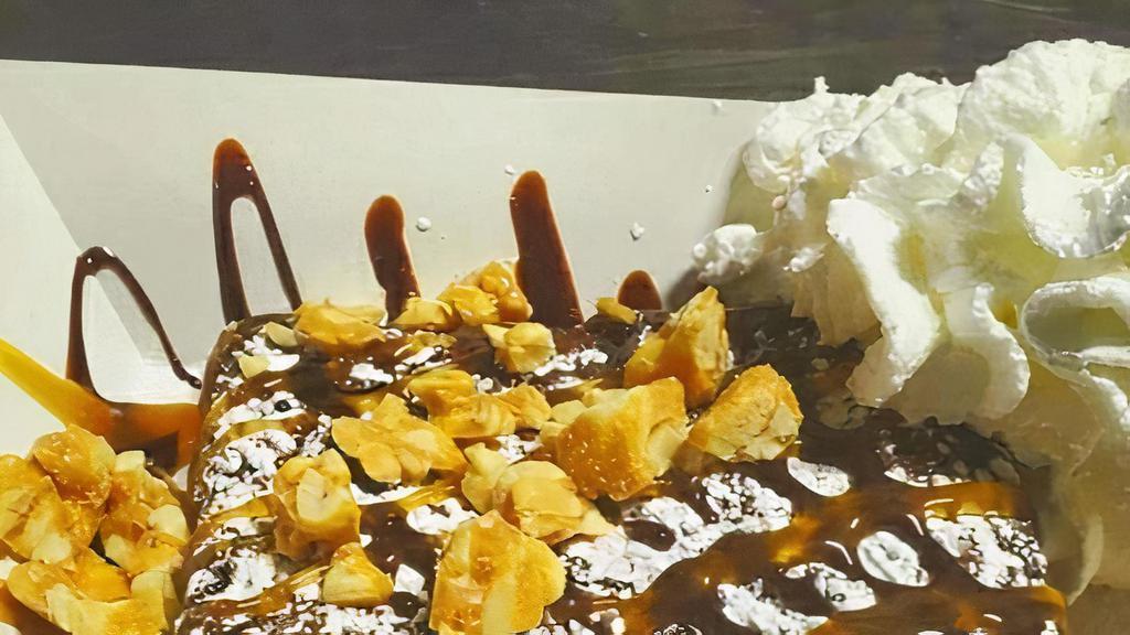 Death By Chocolate Brownie · A triple chocolate chip Brownie topped with chocolate sauce, caramel drizzle, peanut brittle munch,  whipped cream and dusted with powdered sugar