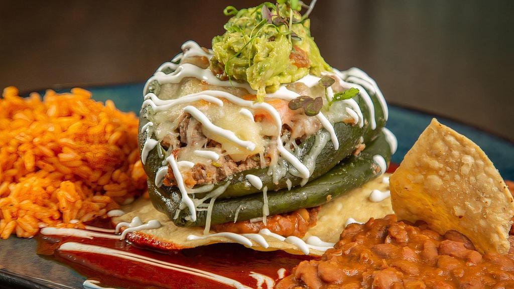 Hussong'S Chile Relleno · Grilled Poblano Pepper, Chopped Steak a la Mexicana, Mexican Cheese Blend, Sour Cream, Guacamole, Crispy Tostada, Guajillo Sauce, Rice, Refried Beans