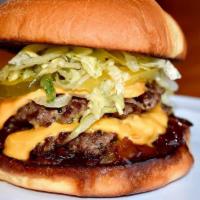 The Shaka Burger · Two smashed beef patties on brioche bun with lettuce, pickles, and onions, and a whiskey bac...