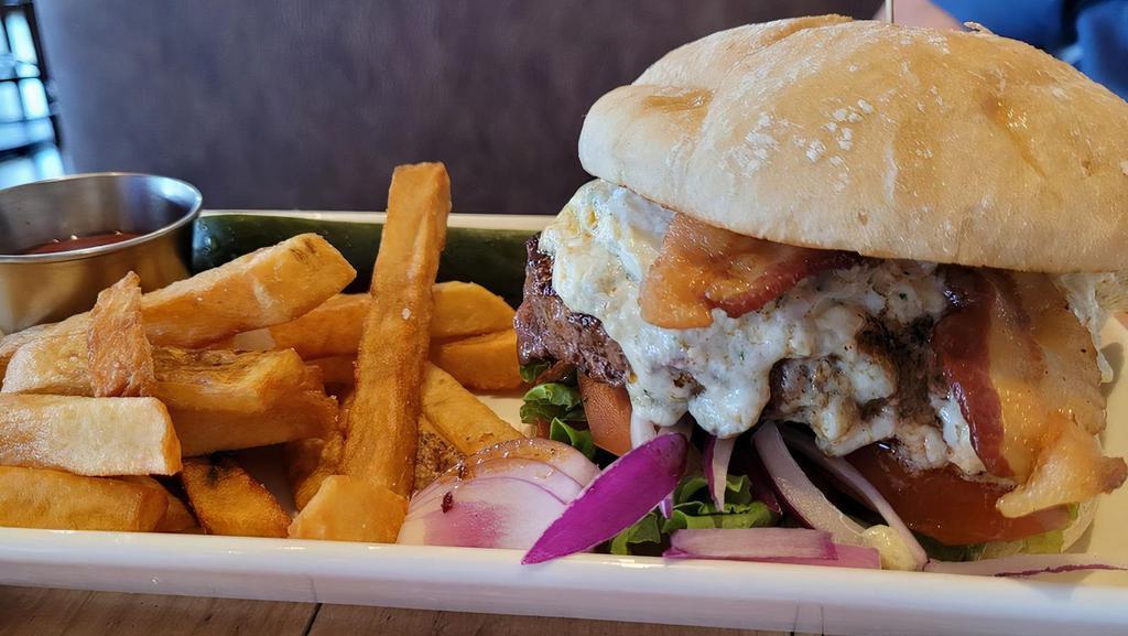 Black & Blue Burger · Blackened Angus beef patty. Topped with bacon, blue cheese, and sat on a bed of crisp lettuce, raw onion and tomato on a European bun. Served with British style chips.