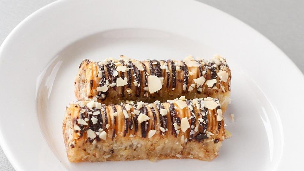 Baklava Chocolate Rolls (2Pc) · Layers of honey glazed crispy phyllo pastry, rolled and filled with crushed nuts and honey, drizzled with chocolate.