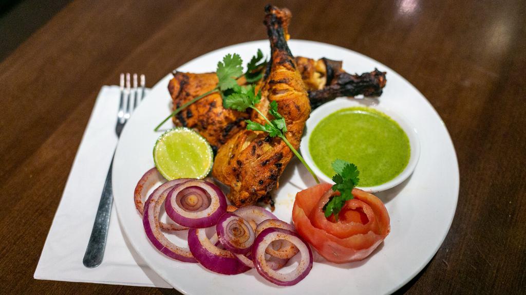 Tandoori Chicken · Chicken marinated in homemade yogurt, ginger, fresh ground spices and tandoor grilled and served with sliced onions and lemon