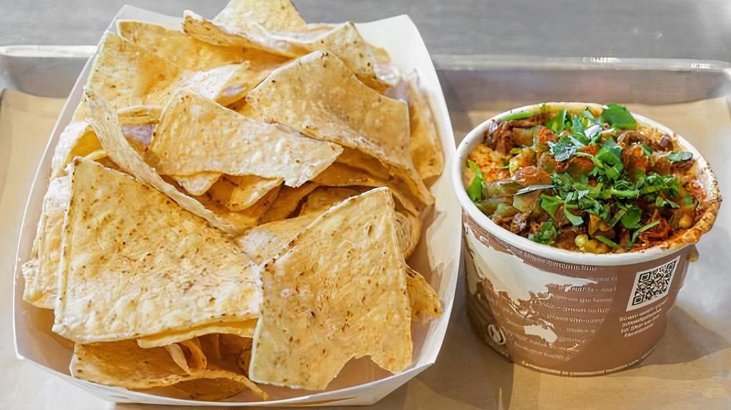 Brisket Queso & Chips · cup of house queso topped with chopped brisket. served with corn tortilla chips.