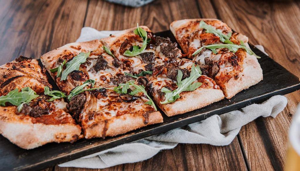 Grilled Wagyu Pizza · Wagyu beef, oven-roasted tomatoes, basil, mozzarella, caramelized onions, spicy red sauce.