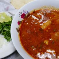 Menudo · The spicy beef tripe soup is accompanied by a side of chopped onion, cilantro, limes and com...