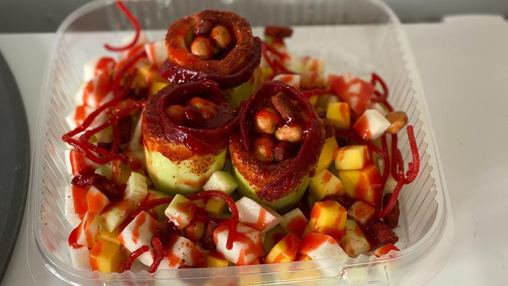 Pepinos Locos · Cucumbers with chamoy and tajin rim filled with tamarind candies, japanese peanuts and chamoy surrounded by mango, cucumbers, chamoy, and tajin
