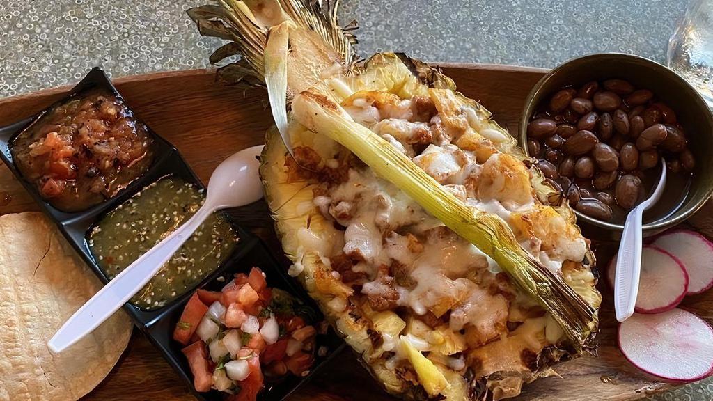 *Piña Al Pastor · Half pineapple that's fire grilled on mesquite and filled with al pastor meat. Topped with melted asadero cheese and served with 3 house salsas, grilled onion, and tortillas.