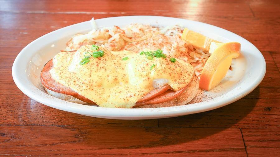 Eggs Benedict · Poached eggs with grilled ham on an English muffin, topped with hollandaise sauce, served with hash browns.