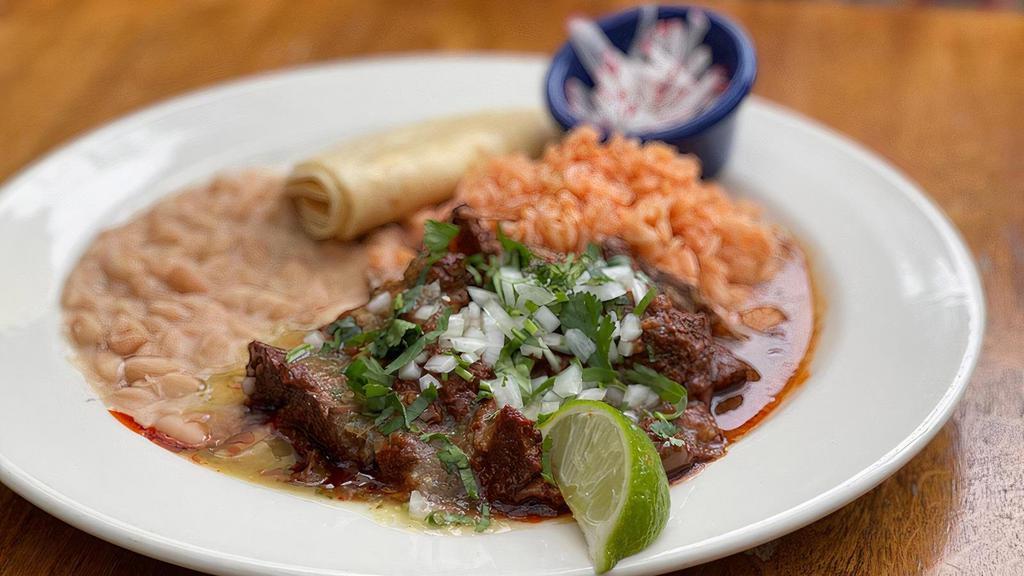 Birria · All-Natural beef slow roasted in acho chile-tomato finished with tomatillos, onion, radish and cilantro, served with Spanish rice and choice of beans, tortillas