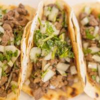 Steak Tacos (3) · Steak Tacos (3) topped with white onions and cilantros and sauces.