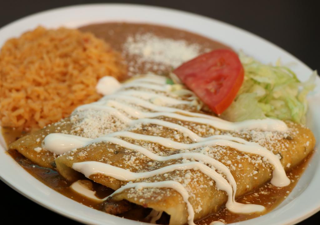 Enchiladas · 3 corn tortillas rolled around a filling covered in a savory sauce topped with cotija cheese and sour cream, served with Rice and beans garnished with lettuce and tomato.