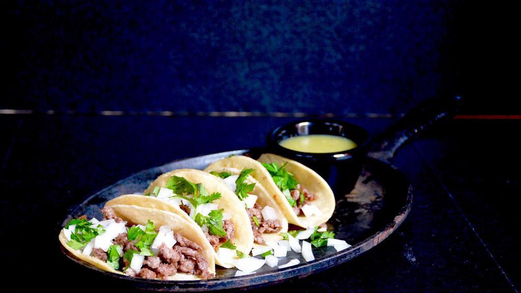 Street Tacos · 4 street tacos filled with chile colorado topping with onions and cilantro served with a side green sauce