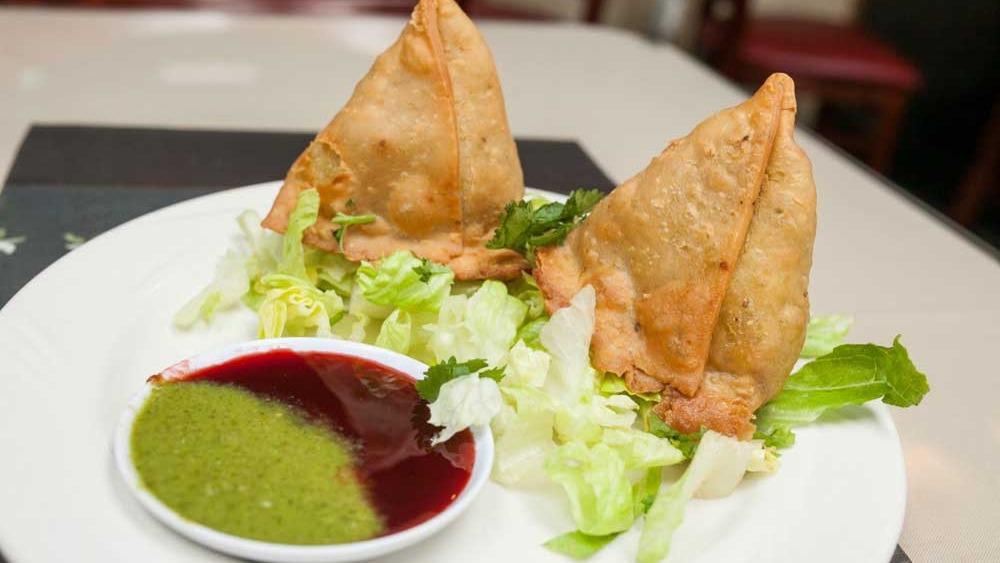 Samosa · Two crispy pastries filled with your choice of freshly mixed vegetables or delicately spiced lean ground beef.