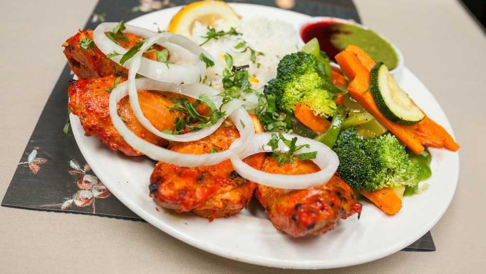 Tandoori Chicken Breast · Gluten-free, halal. Juicy spring boneless chicken breast marinated with yogurt and fresh ground spices. Served with sliced onions and lemon, basmati rice, fresh vegetables, and our famous cilantro and tamarind chutneys.