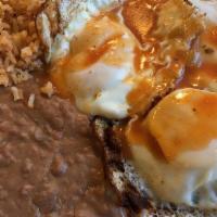 Huevos Rancheros · Three eggs with sauce on a fried tortilla.