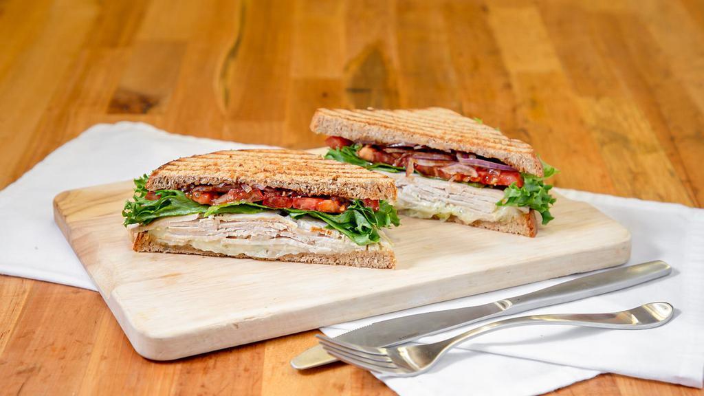 Turkey Pesto Supreme Sandwich · Flavors abound in this turkey sandwich! Loaded with our fresh baked turkey, swiss cheese, pesto, tomatoes, red onions, leafy green lettuce, drizzled with balsamic and spread with best foods mayonnaise and grey poupon mustard.