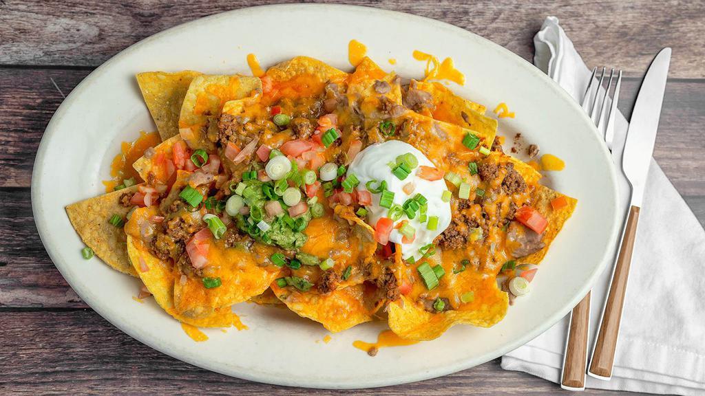 Super Nachos · Crisp corn chips, topped with melted cheese, refried beans, fresh tomato, guacamole, and sour cream.