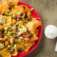 Nachos · A heaping pile of crisp yellow tortilla chips covered in melted cheddar and jack cheese, top...