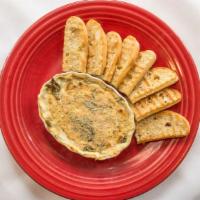 Wood Oven Artichoke Dip · Creamy spinach artichoke dip topped with parmesan and toasted bread crumbs. Served with gril...