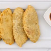 Huushuur · 4 pieces of deep-fried beef flat pies served with sliced tomato and cabbage salad.