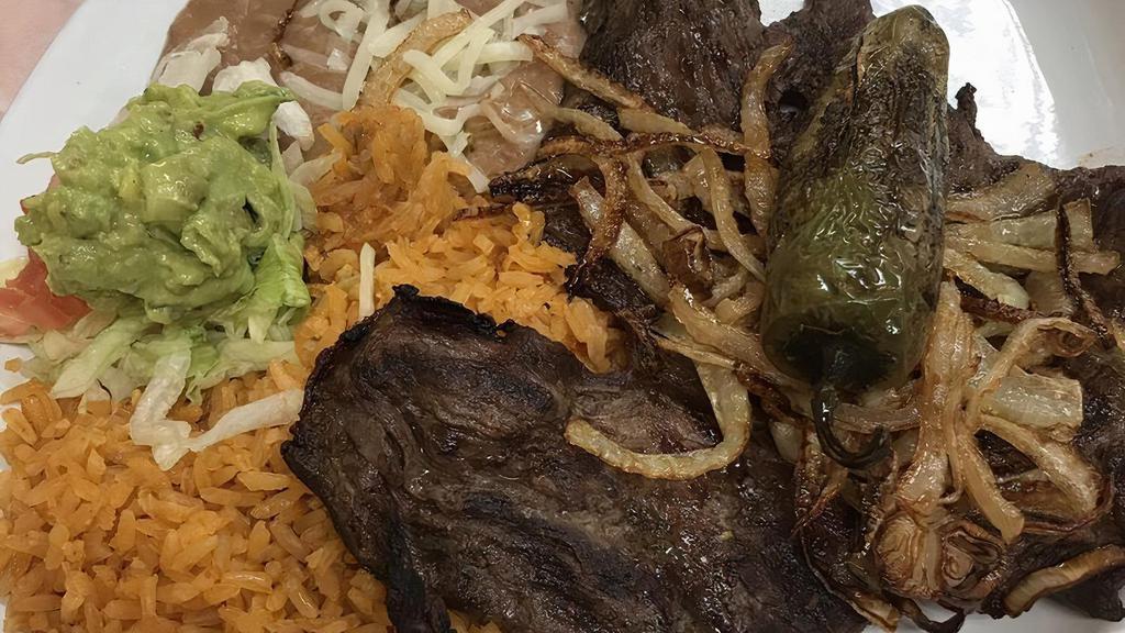 Carne Asada · steak char=broiled and garnished with grill onion and jalapeno. served with rice and beans, guacamole, sour cream, corn or flour tortillas.