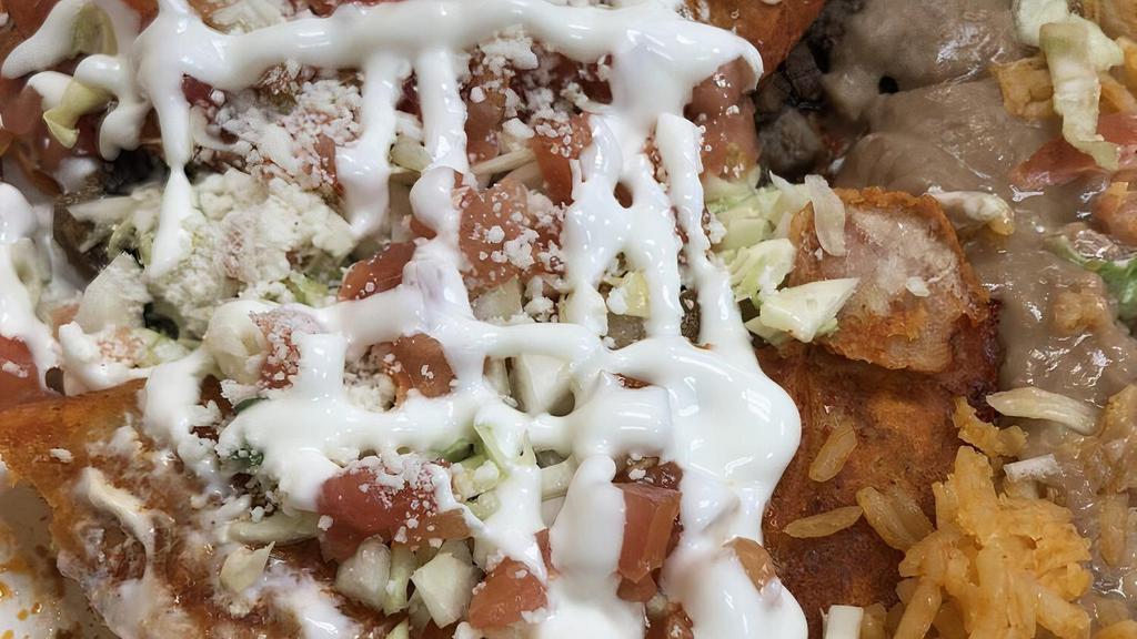 Enchiladas Rancheras · 2 enchiladas bathed in adobo and filled with cheese,choice of meat, garnished with cabbage, onion, cilantro, tomato, sour cream, cheese. served with beans and rice.
