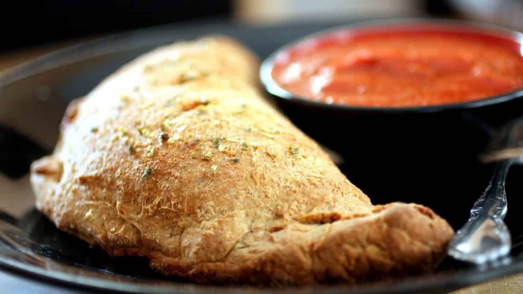 Stromboli Calzone · The meaty version of the calzone. Stuffed with ham, salami, onions, bell peppers, black olives, provolone and mozzarella cheeses. Served with a side of marinara.