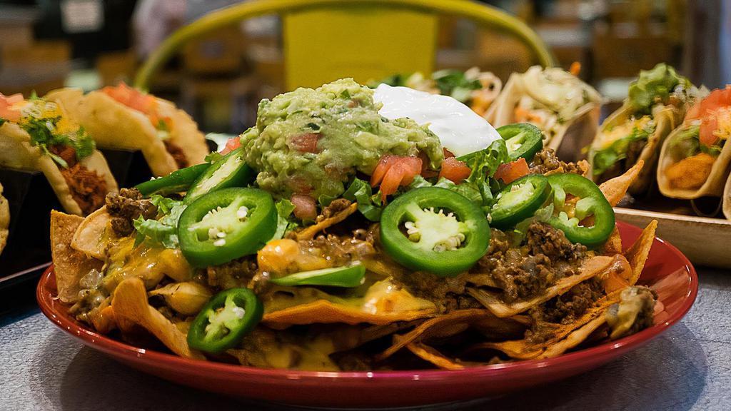 Loaded Nacho · House made tortilla chips layered with shredded cheese, pinto beans, and Chile con Queso, and ground beef topped with lettuce, tomatoes, guacamole, sour cream and sliced jalapeños.