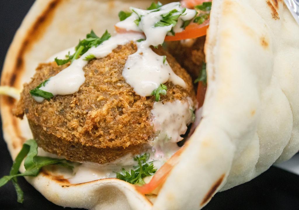 Falafel Sandwich · Delicious, golden falafel balls quickly deep fried and wrapped in a Greek pita with hummus, tahini sauce, lettuce, and tomato.