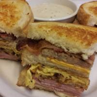 Frontier Breakfast Sandwich · One of a kind tripledecker on homemade bread stacked with extra crispy hashbrowns, ham, baco...