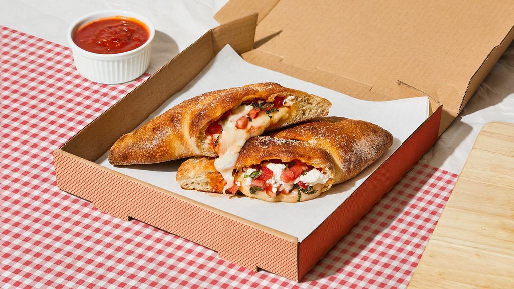 The L Train Calzone · Calzone with creamy ricotta, parmesan cheese, melted mozzarella, tomato, basil, and a side of marinara.