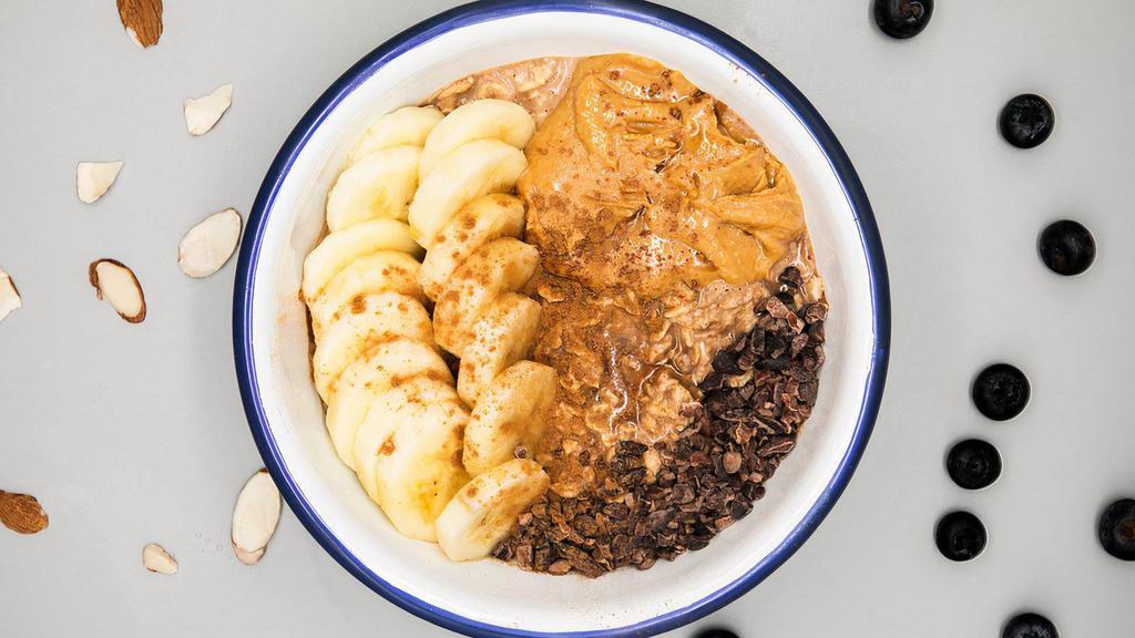 Peanut Butter Cacao Oatmeal · 100% organic peanut butter cacao oatmeal made with rolled oats, house cashew milk, cacao powder, house peanut butter, sliced banana & maple<br />