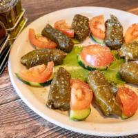 Dolmadakia · Stuffed grape leaves with rice served with tomato and cucumber.
