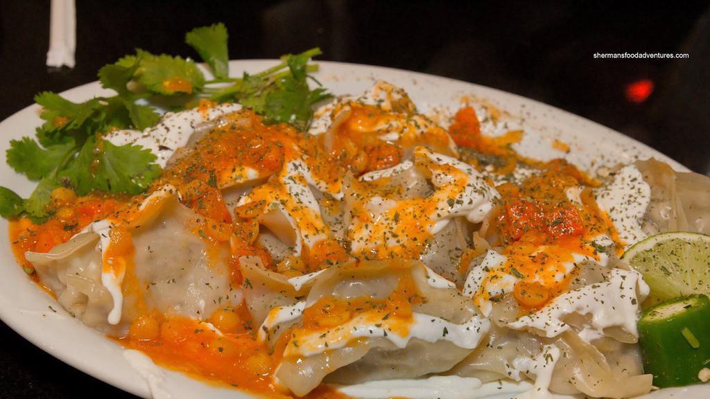 Mantu · Onion and ground lamb filled steamed dumplings, topped with yogurt, and served with mixed vegetables.