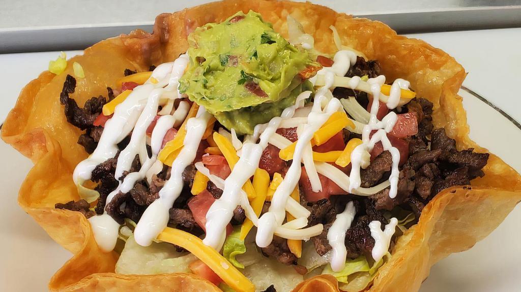 Taco Salad · Large round shell filled with beans, rice, lettuce, diced tomatoes, shredded cheese, sour cream, guacamole, and your choice of meat.