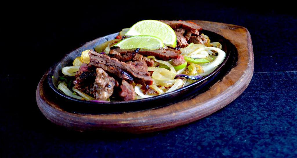 Steak Fajitas · Steak fajitas are served sizzling hot over a bed of sauteed onions and green peppers. Accompanied with rice, black beans, refried or rancho (whole) beans, pico de gallo, sour cream, guacamole, cheddar cheese. Substitute rice and beans with steamed veggies, house salad or Azteca fries.