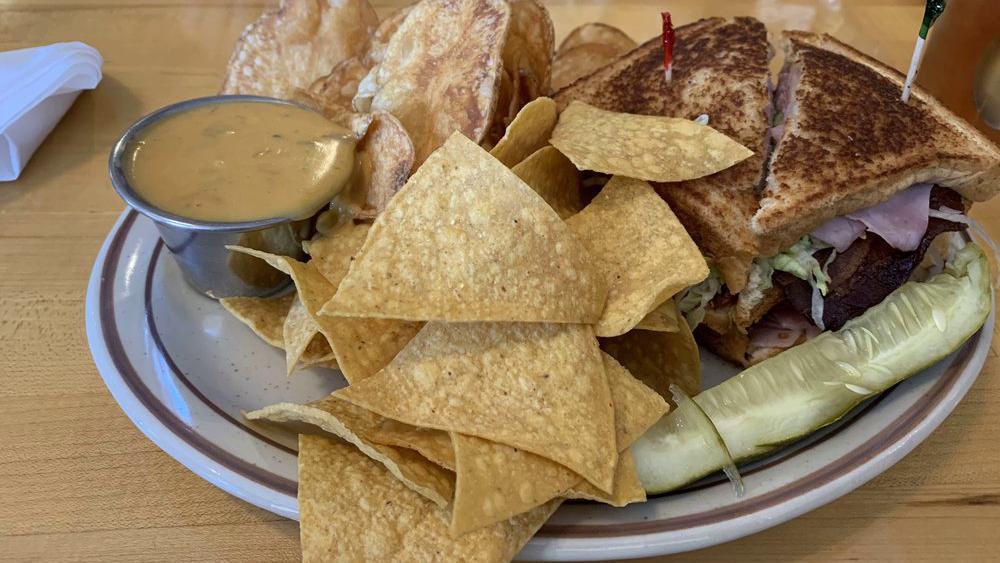 Country Club · Triple decker ham, turkey, and Swiss cheese topped with bacon, lettuce, and tomatoes, then grilled on whole wheat to perfection. Accompanied by a side of chile con queso and chips.