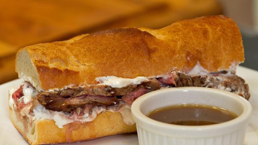 French Dip Au Jus Sandwich · Deluxe roast beef, melted Vermont yellow cheddar, pepperoncini, red onion and horseradish mayo, served on a toasted Italian sub roll with a steaming cup of au jus for dipping. COMBO COMES WITH YOU CHOICE ,POTATO SALAD,CIPS,MAC SALAD