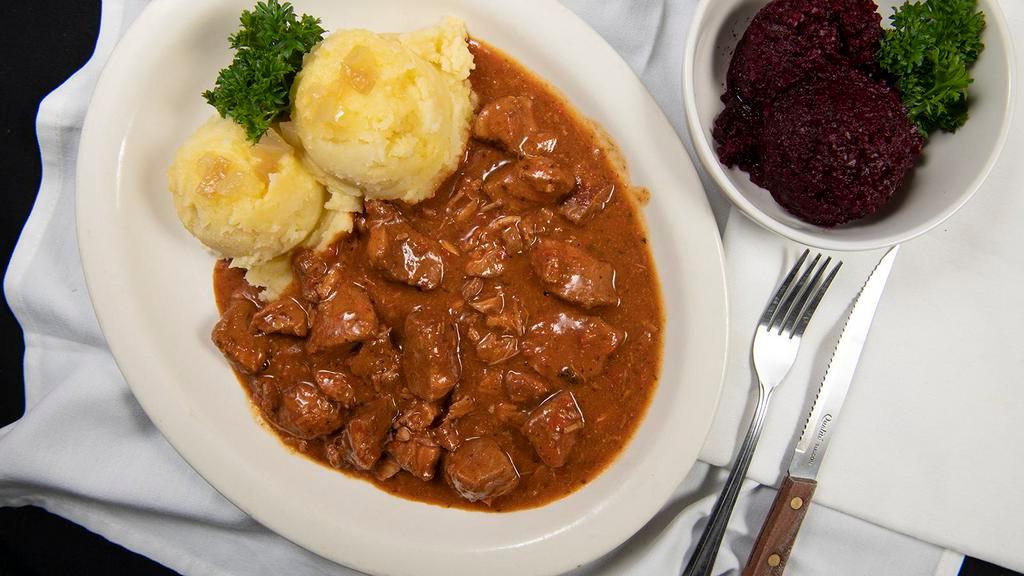 Gulasz · Tender chunks of pork, braised in a hearty paprika sauce, your choice of beets or mizeria