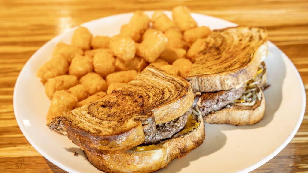 Classic Patty Melt · Toasted rye bread, seasoned American Wagyu steak patty, salty and slightly sweet onions, melted cheddar cheese, and secret sauce. Served with a side of tater tots. Add bacon for an additional charge.
